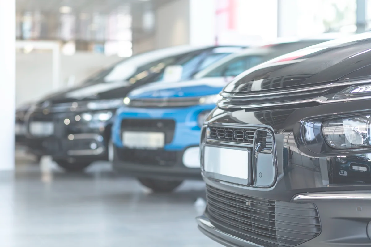 concesionario-coches-nuevos-limpios Primer plano de varios coches nuevos alineados en un concesionario, mostrando limpieza y profesionalismo.